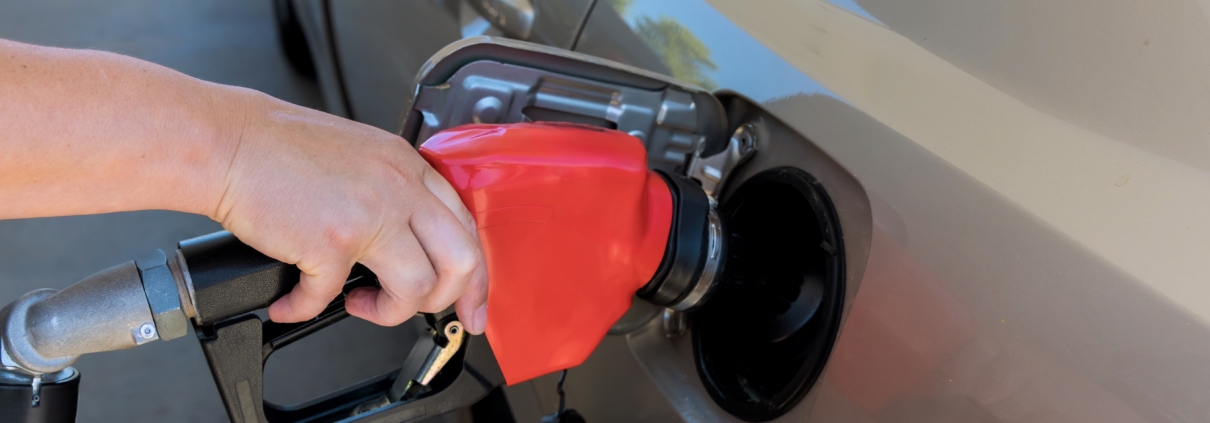 Worker,Hand,Holds,Red,Gas,Nozzle,As,It,Pumps,Fuel